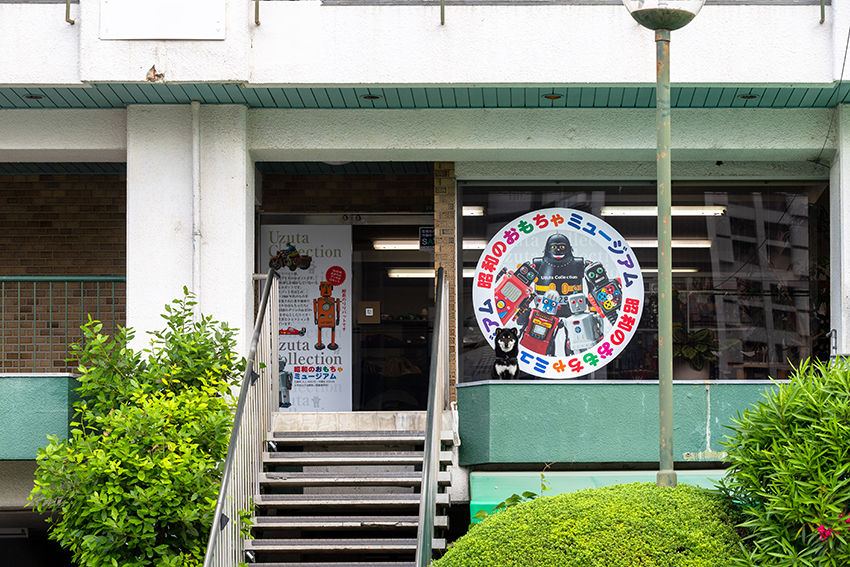 昭和のおもちゃミュージアム入口　マンション正面の階段を上がるとすぐ入口があります。階段の使用が難しい場合は、エレベーターもあります。
気候の良いときは看板犬・太郎が入口横でお迎えします！